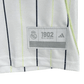 Real Madrid baseball style shirt showing iconic black Adidas three stripes on shoulders with premium white base fabric and sporty aesthetic